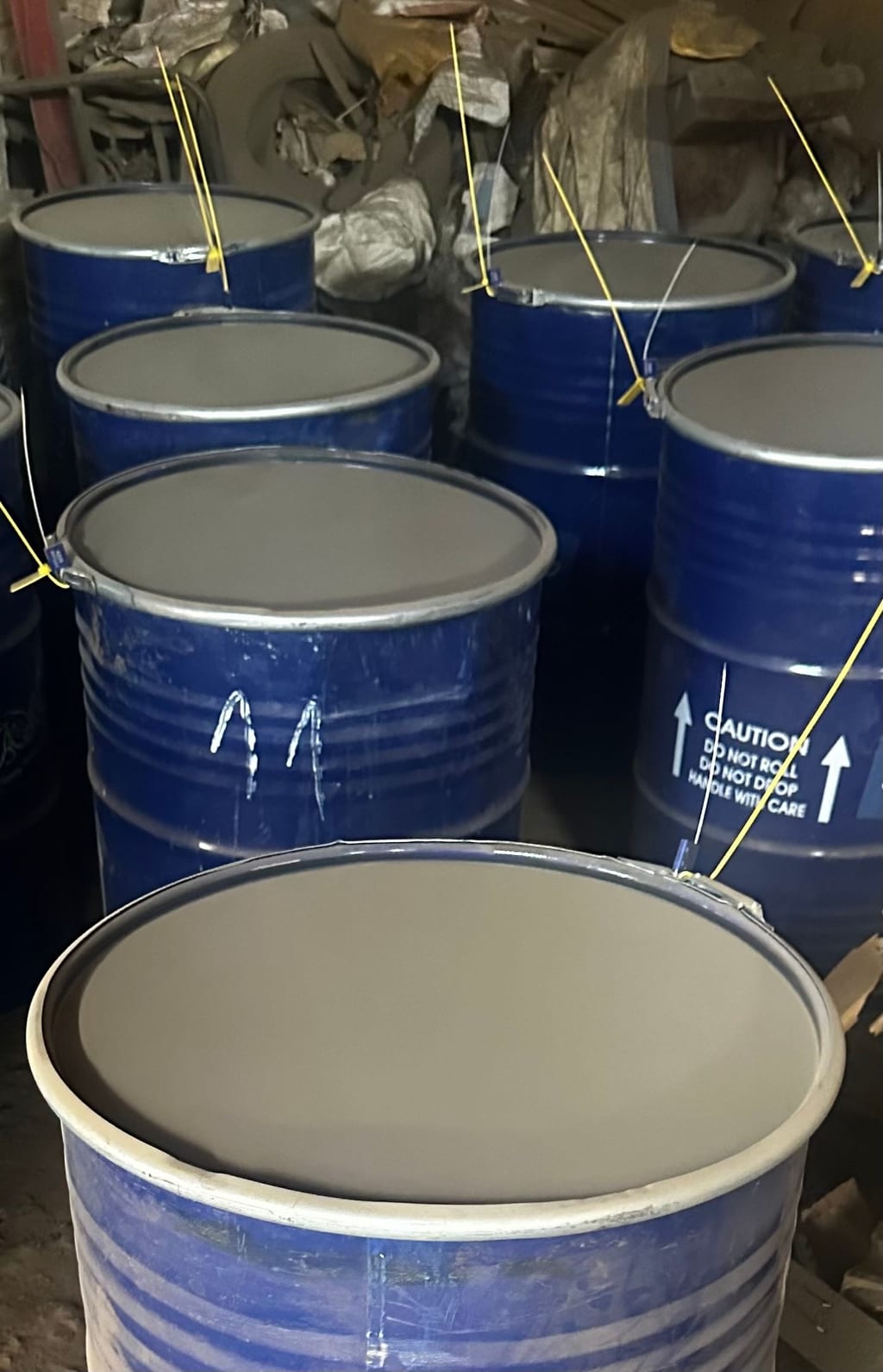 Sealed and tagged steel drums of mineral concentrate prepared for export.