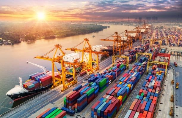 A container terminal at sunrise, with ship-to-shore cranes loading cargo.